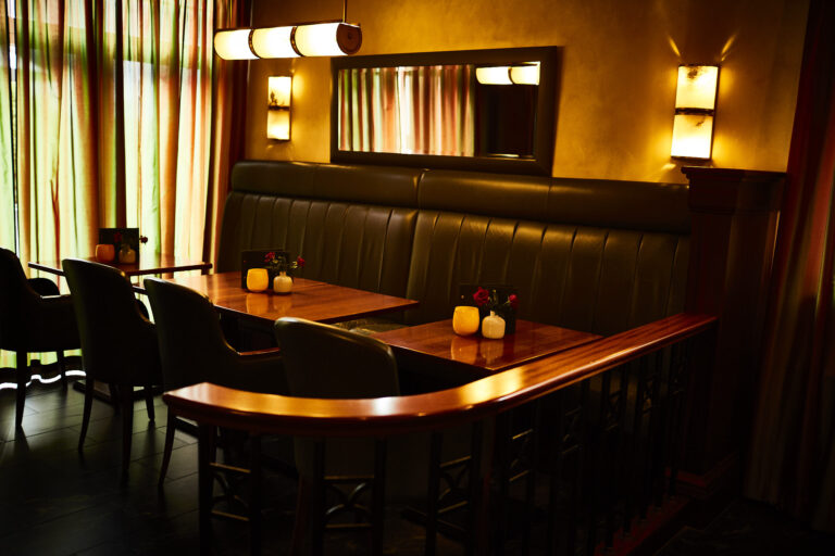 The Deck 48 bar impresses with its cosy furnishings, including wooden tables, upholstered chairs, warm lighting, a long mirror on the wall and small vases of flowers and candles on the tables. Floor-length curtains cover the large windows.