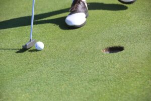 Close-up of a golf ball being hit towards the hole with a golf club.